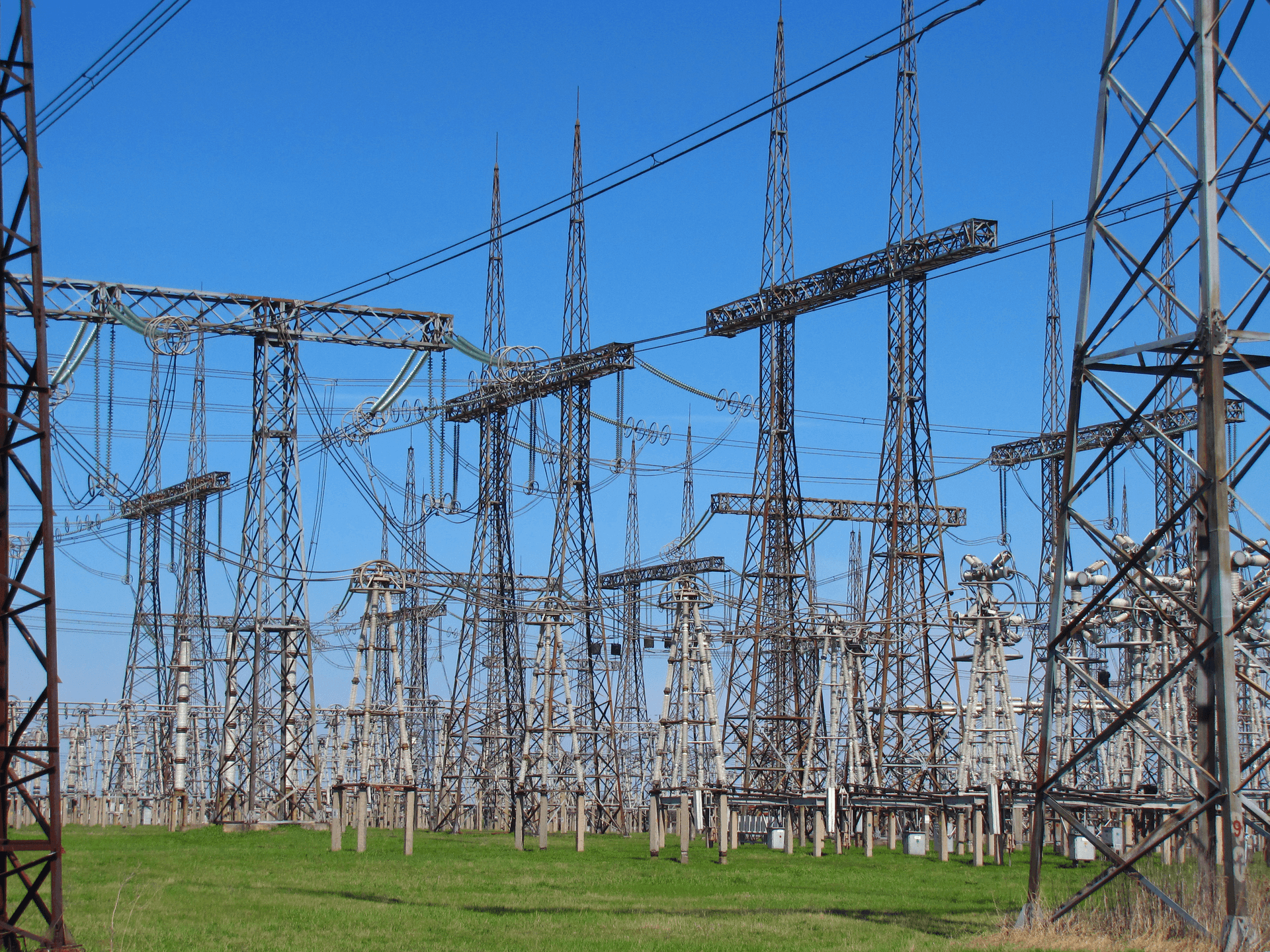 High-voltage switchyard with rows of steel transmission towers and power lines under a clear sky