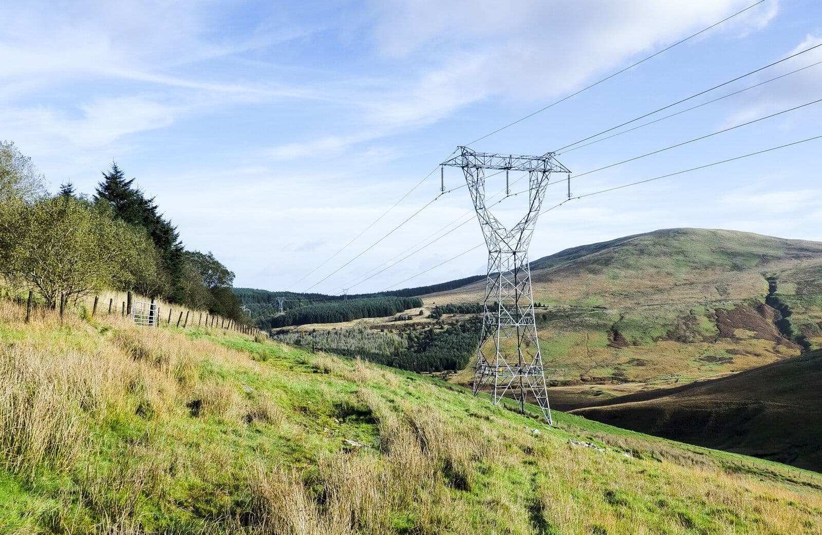 High-voltage transmission tower and power lines stretching across a hillside landscape