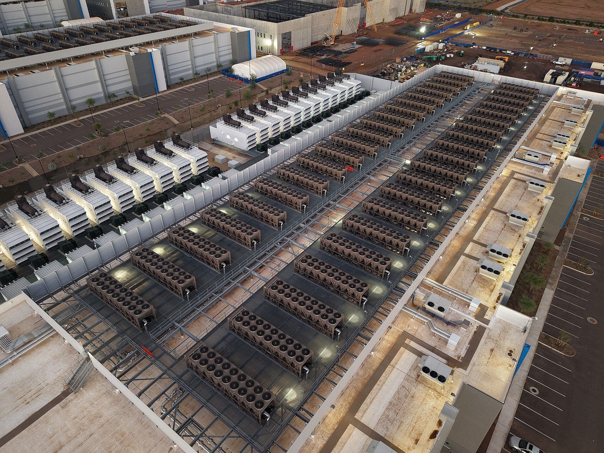 Aerial view of a large data center roof with extensive rows of cooling towers and backup generators