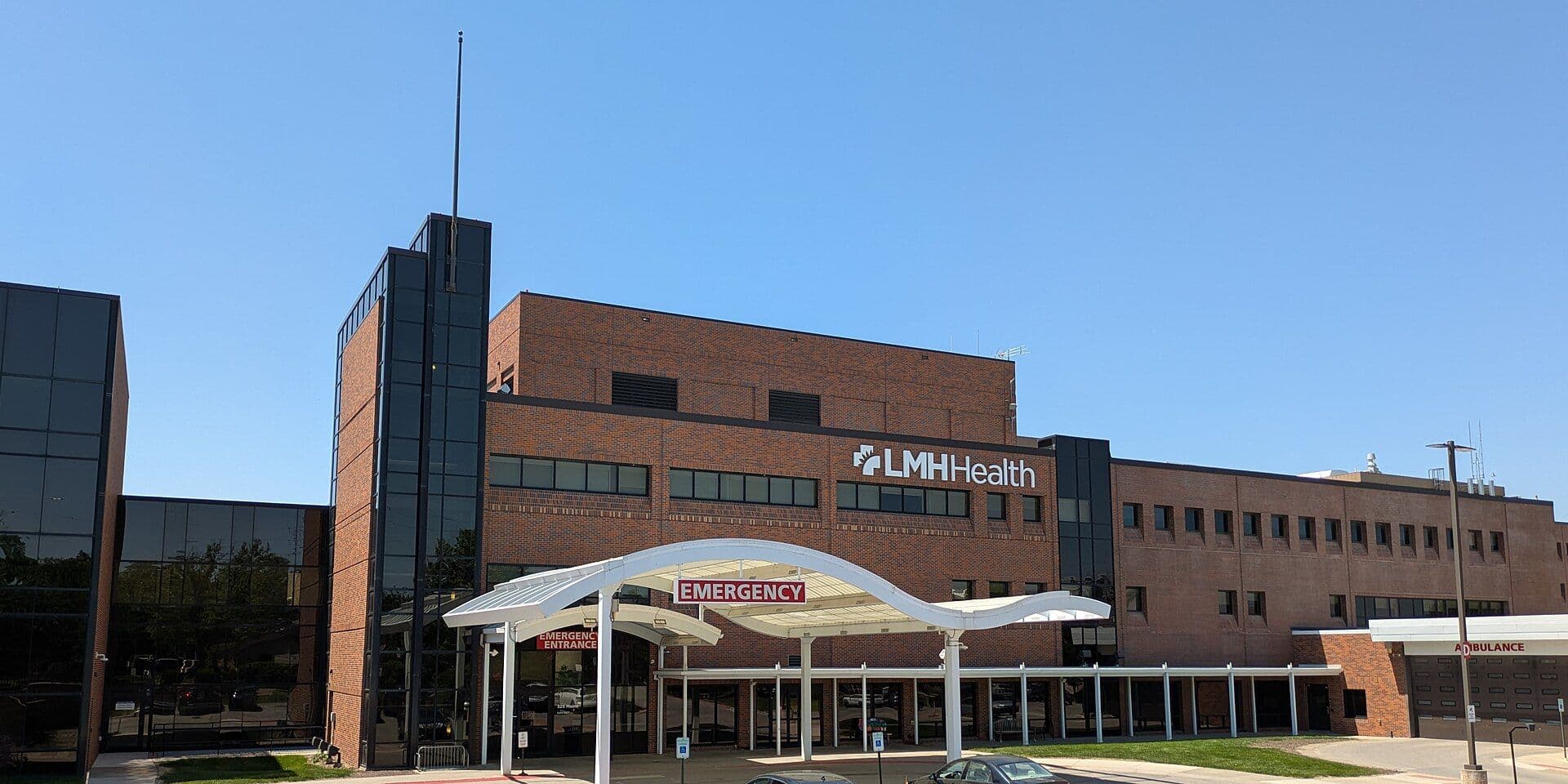 Hospital emergency department entrance with brick building facade and white curved canopy