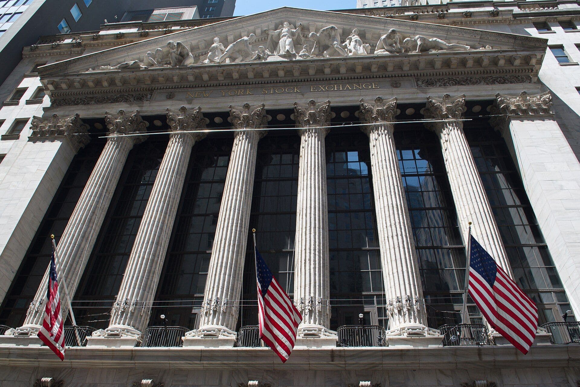 Front facade of the New York Stock Exchange building with columns and American flags