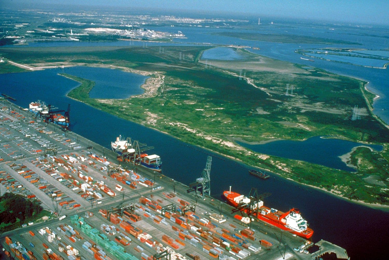 Container terminal with stacked cargo boxes, cranes, and cargo ships docked at port