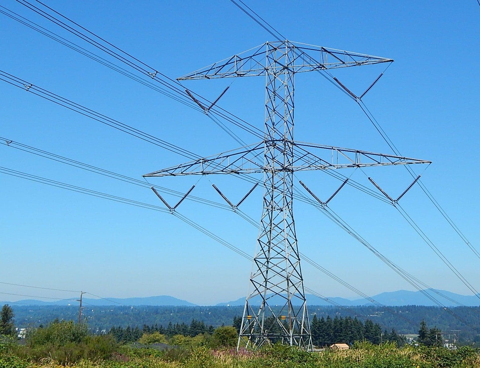 High-voltage transmission tower against clear blue sky with multiple power lines extending across landscape