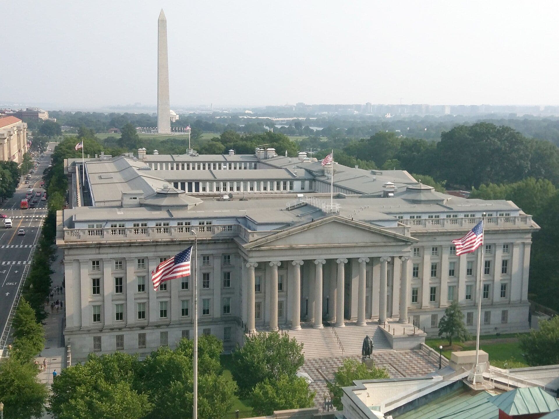 Aerial view of the Treasury Building in Washington, D.C. with the Washington Monument in the background.
