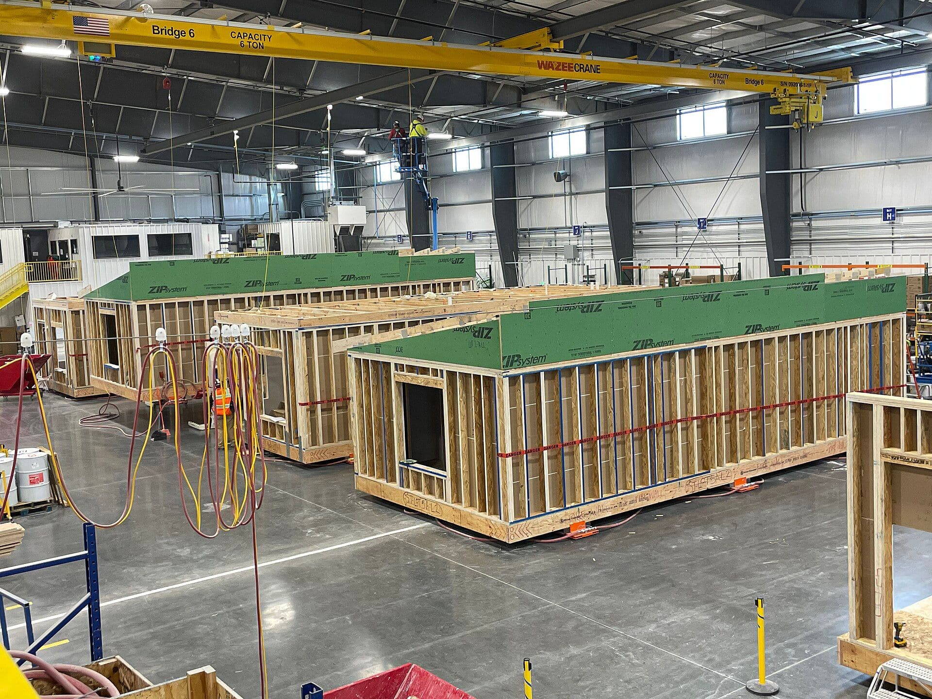 Modular homes under construction with overhead crane in industrial facility