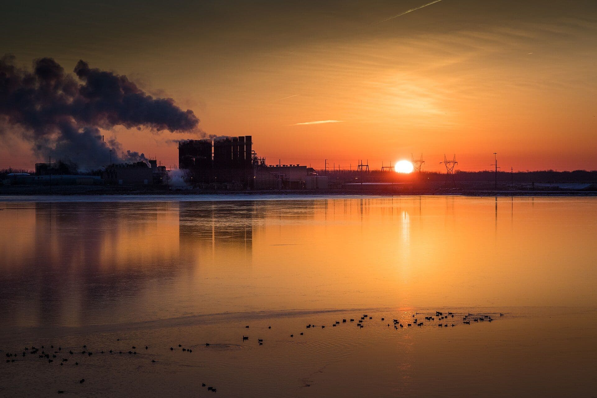 Power plant reflected in water at sunset
