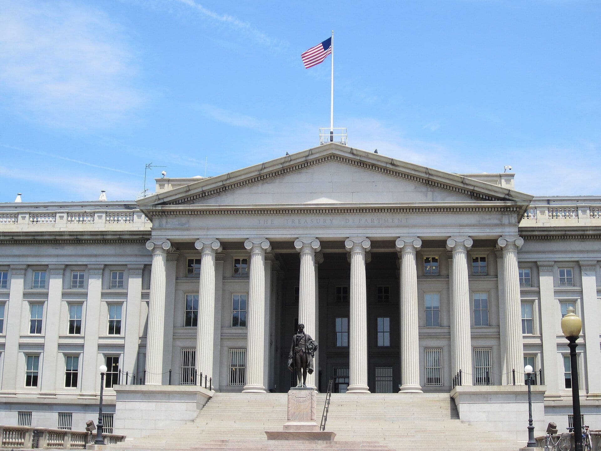 The Treasury Department building's classical white facade with tall columns in daytime