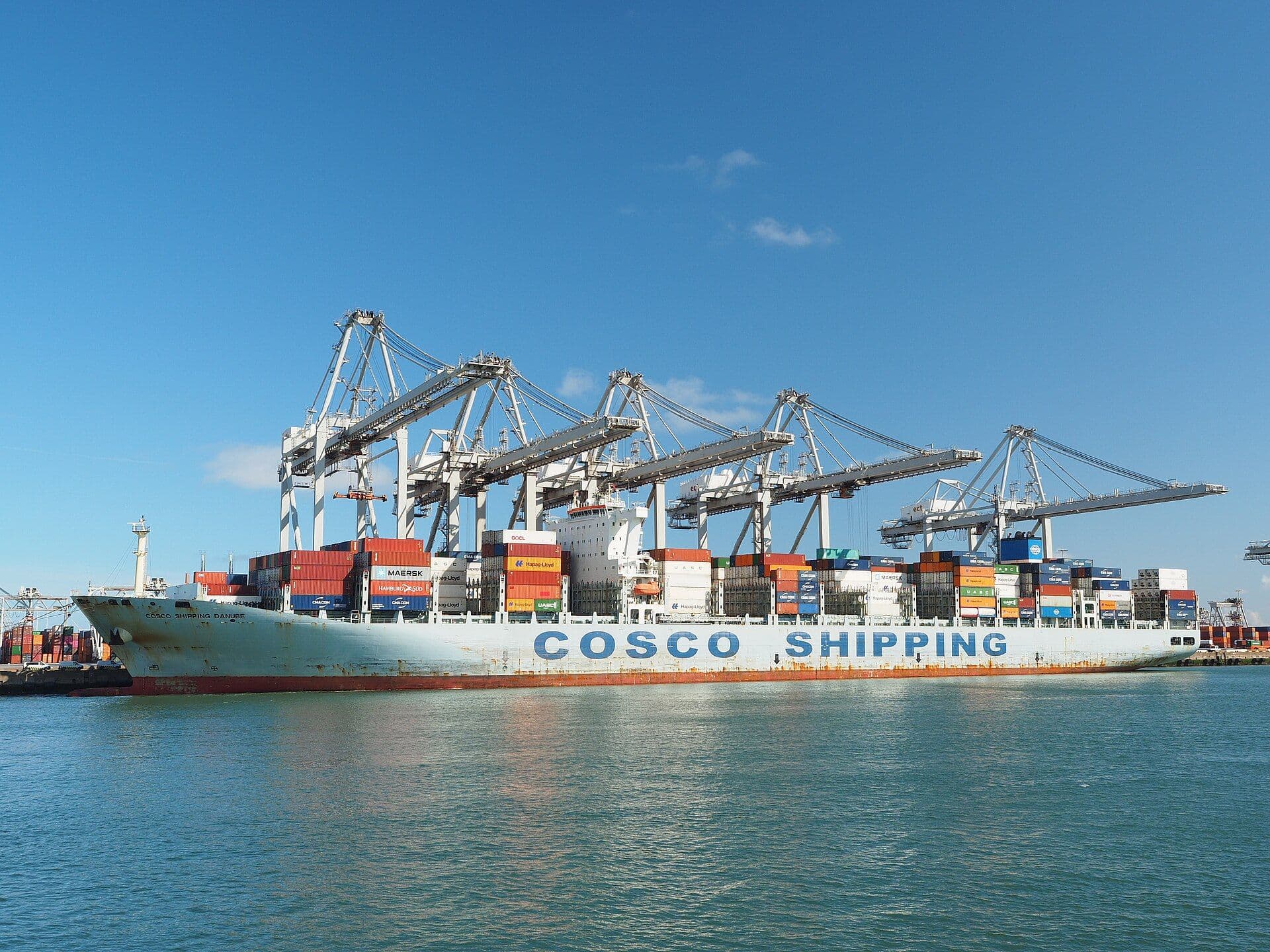Container ship loaded with shipping containers docked at port with gantry cranes