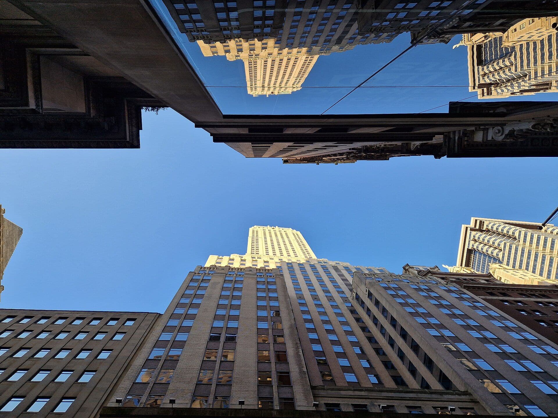 Looking up at tall modern skyscrapers from street level with blue sky