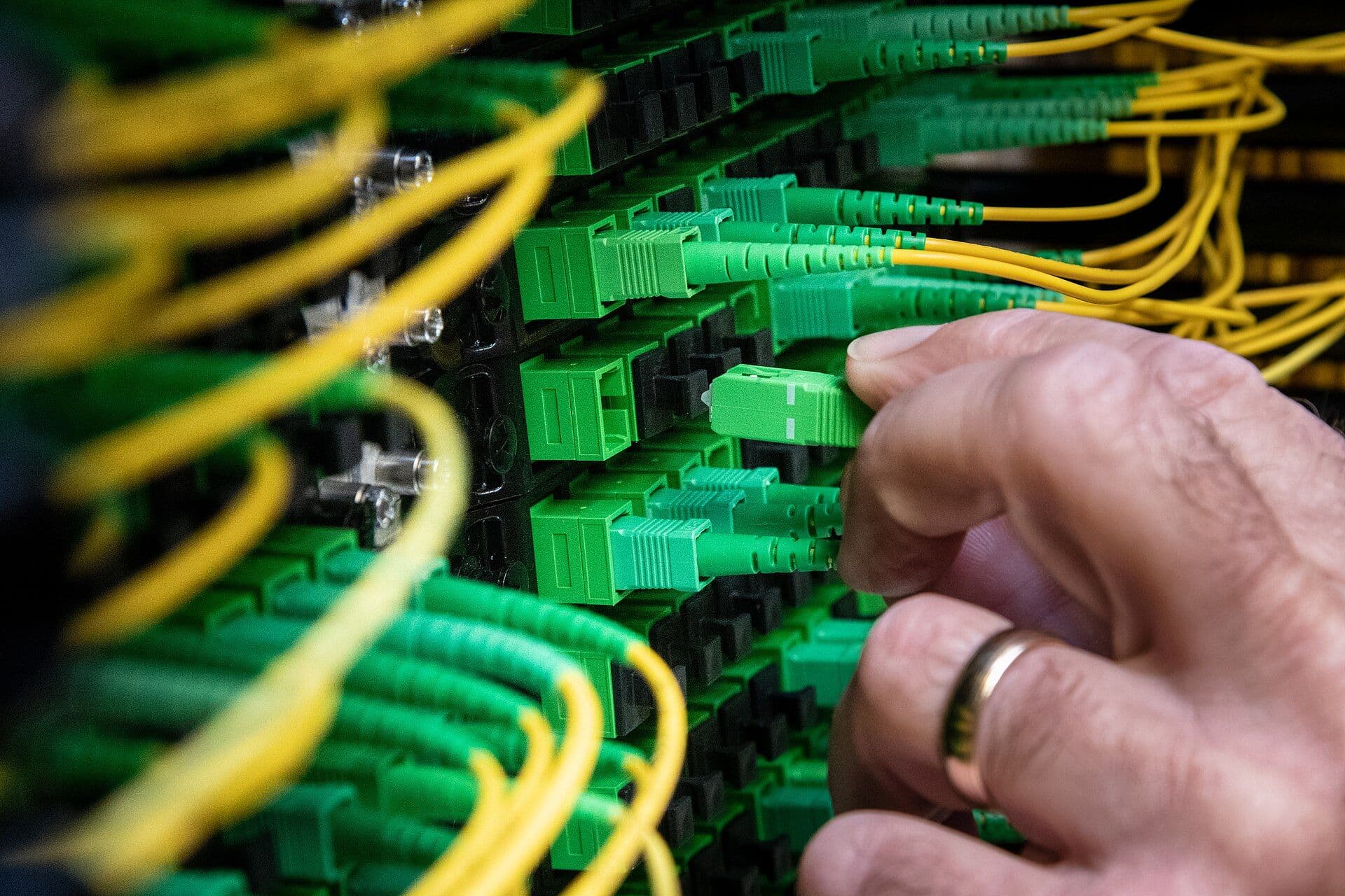 Close-up of fiber optic cables with green and yellow connectors in a data center installation