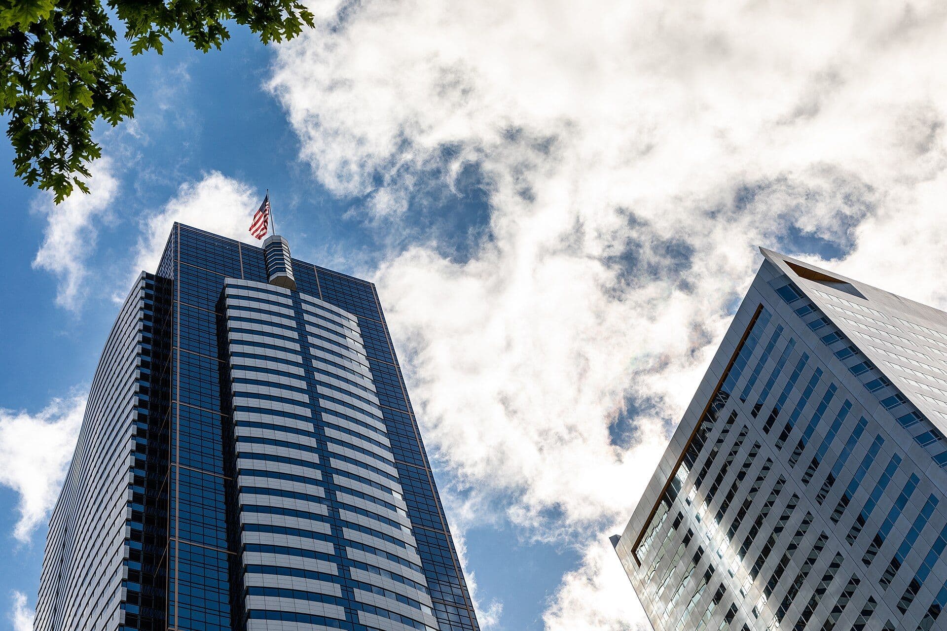 Modern office buildings photographed from below against a blue sky with clouds